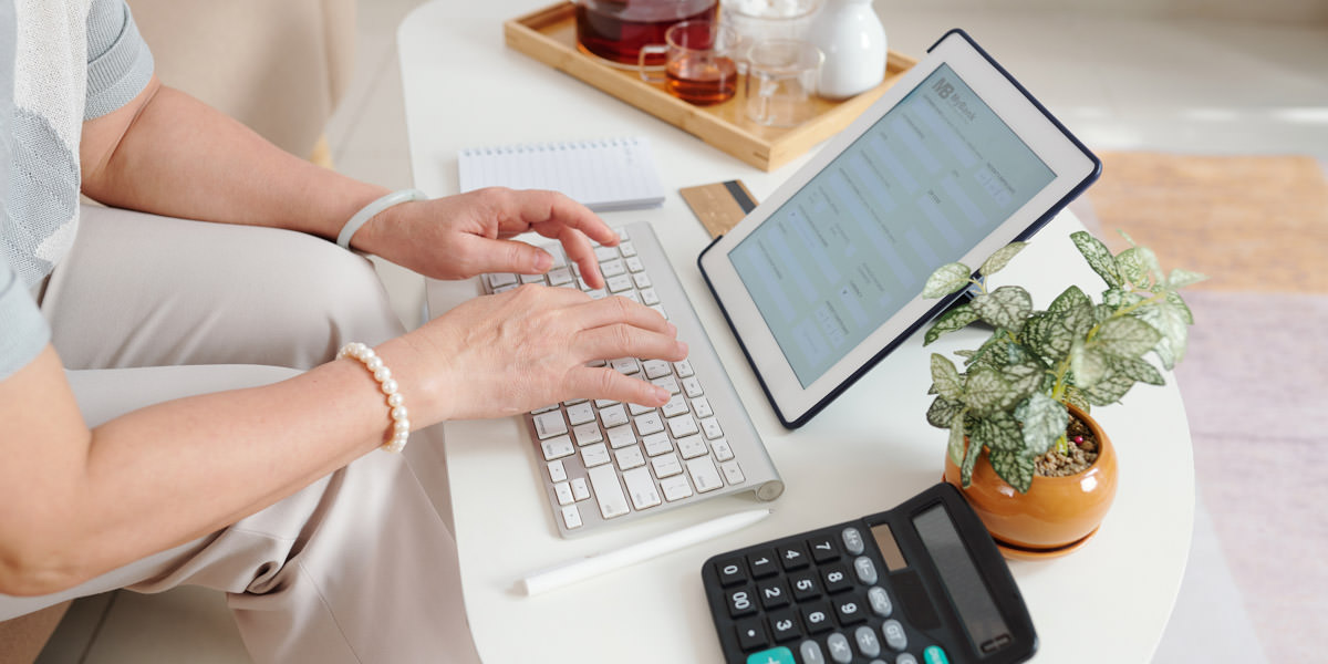 Digitale Buchhaltung Frau sitzt vor dem iPad und tippt auf einer Tastatur