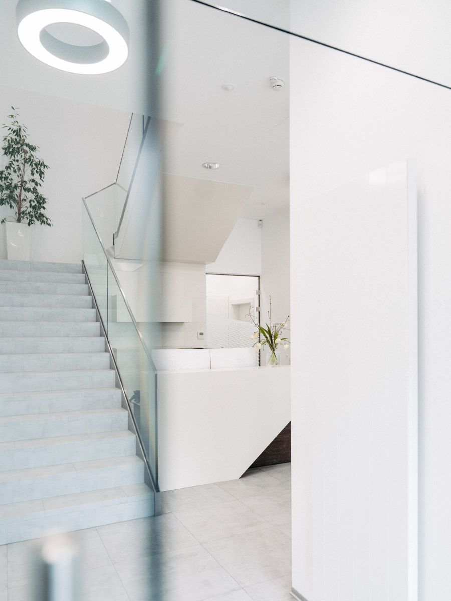 Moderner Eingangsbereich mit Treppe und Glas – vermittelt Offenheit, Struktur und Vertrauen