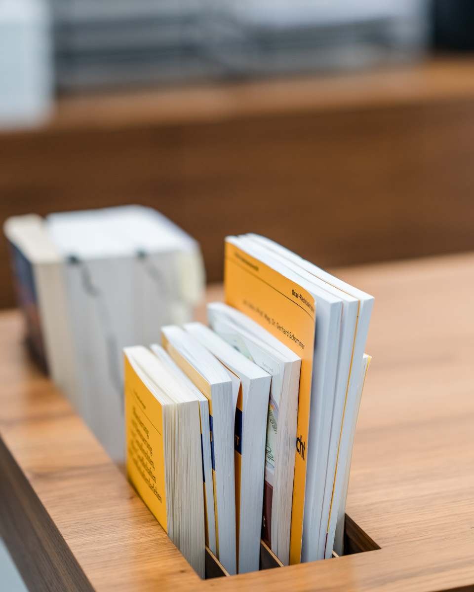 Fachbücher zur Steuer- und Arbeitsrecht im Holzregal – symbolisieren Fachwissen in der Lohnverrechnung