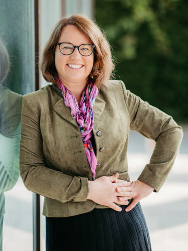 Porträt von Renate Gruber, Teammitglied der Südsteirischen Steuerberatung, freundlich lächelnd vor Glasfassade