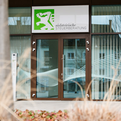 Eingang der Kanzlei mit Logo auf der Glastür – steht für Verlässlichkeit und Offenheit